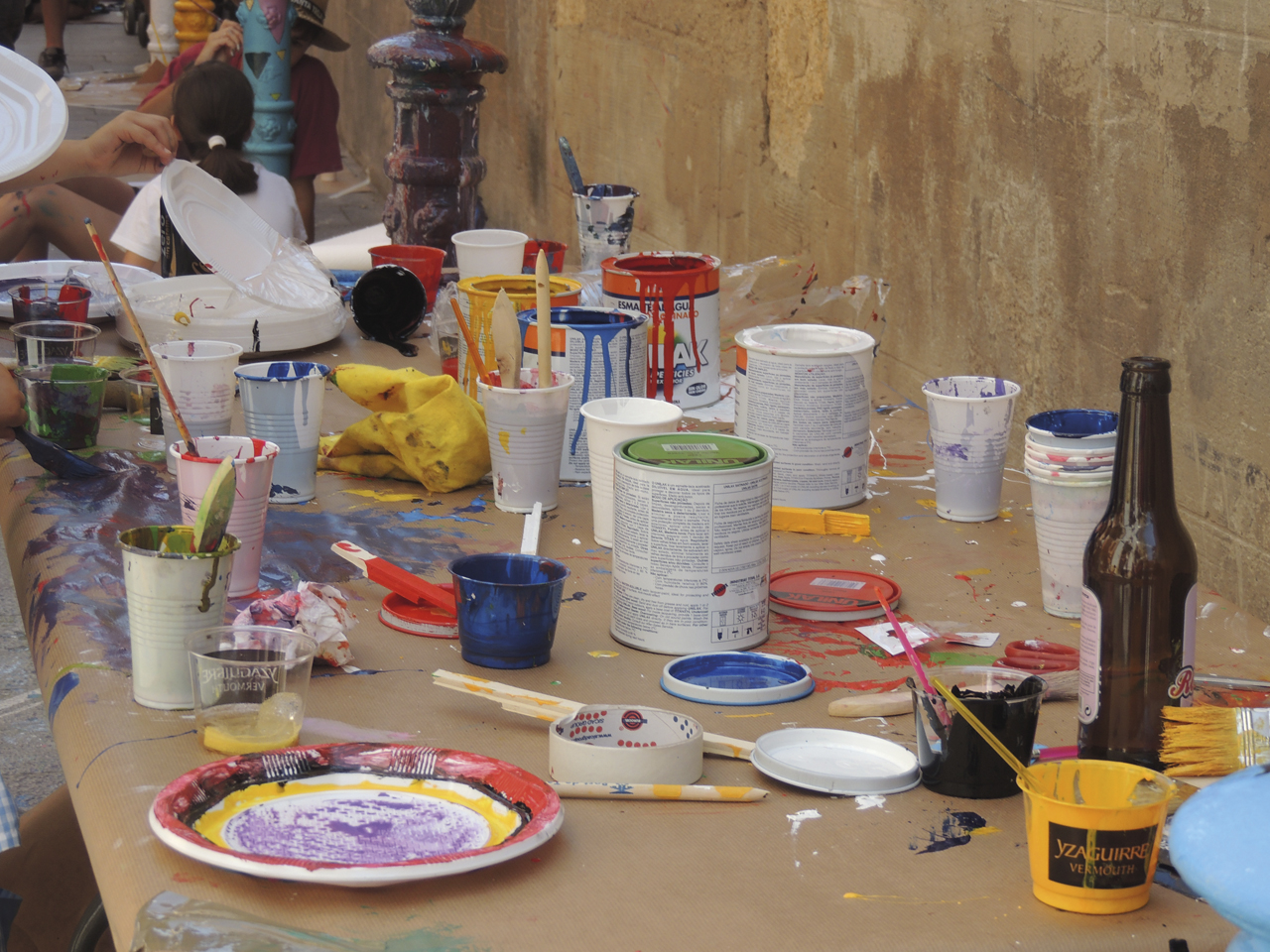 Una taula repleta de pots i estris per pintar.